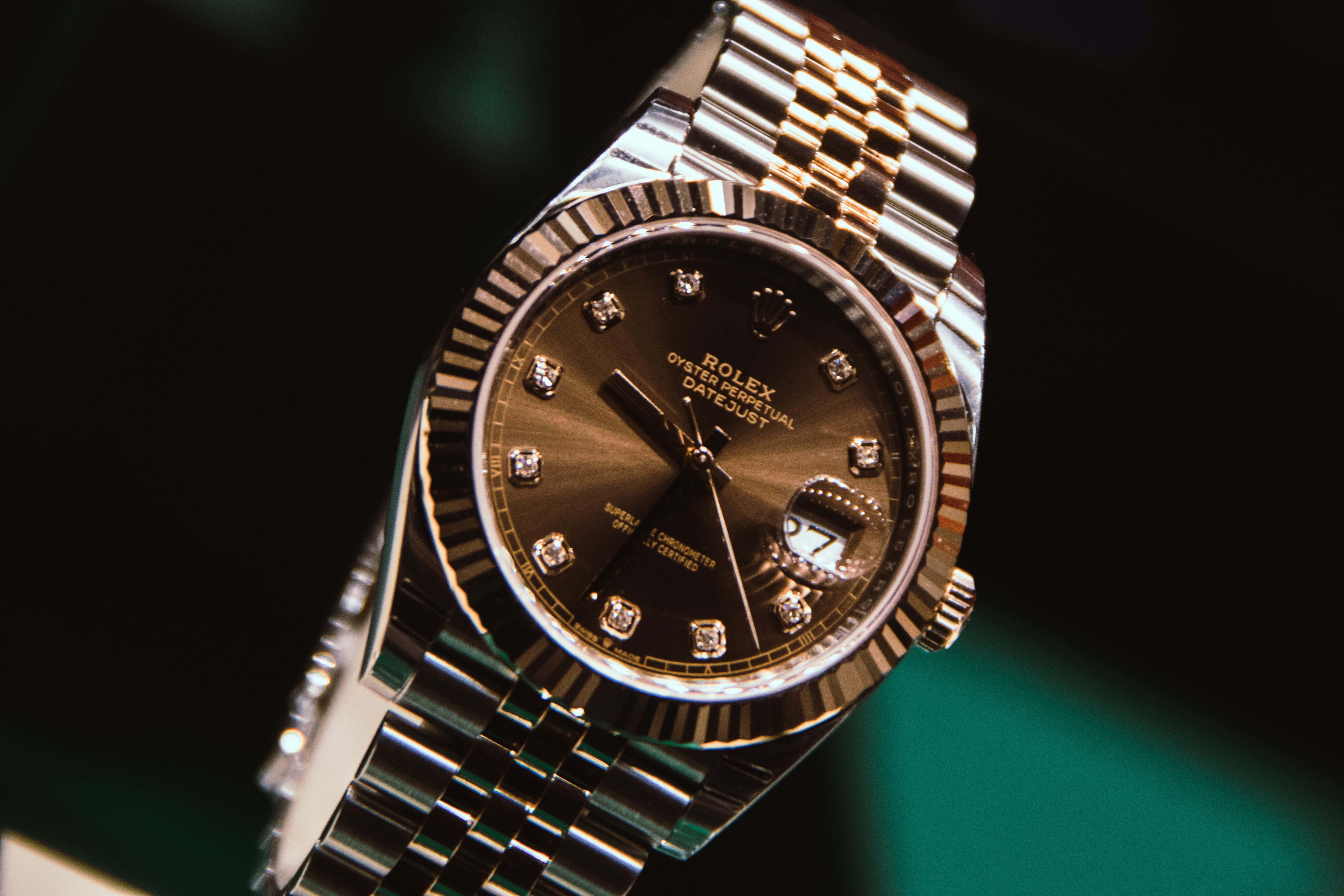 Rolex watch photographed in dark studio light, showing the case, dial, and bracelet from a three-quarter angle